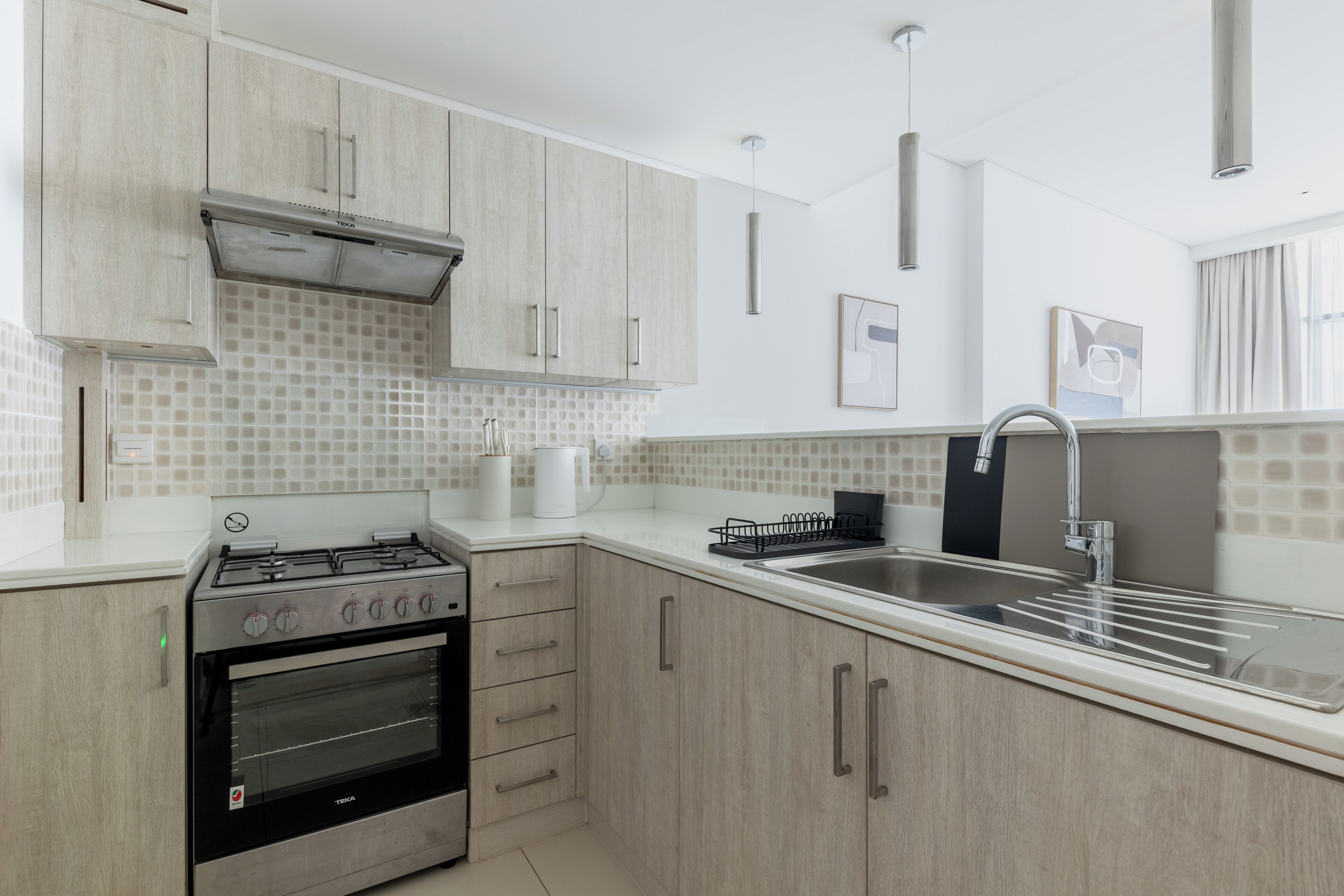 Une cuisine moderne avec des meubles de couleur bois clair, une cuisinière en acier inoxydable et un évier à deux bacs.