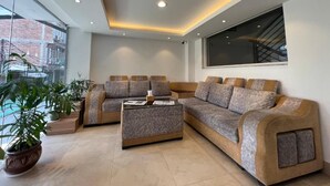 A modern living room with a sectional sofa, a coffee table, and potted plants. - Hotel New Era (Kathmandu)