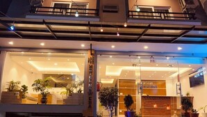 A hotel entrance with a modern design, featuring a glass facade, a staircase leading to the upper floors, and potted plants at the base. - Hotel New Era (Kathmandu)