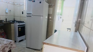 A kitchen with a refrigerator, oven, and gas stove.