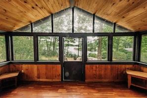 A wooden interior with large windows, a bench, and a door. - Harriman Outdoor Center - Stone Lodge (Haverstraw)
