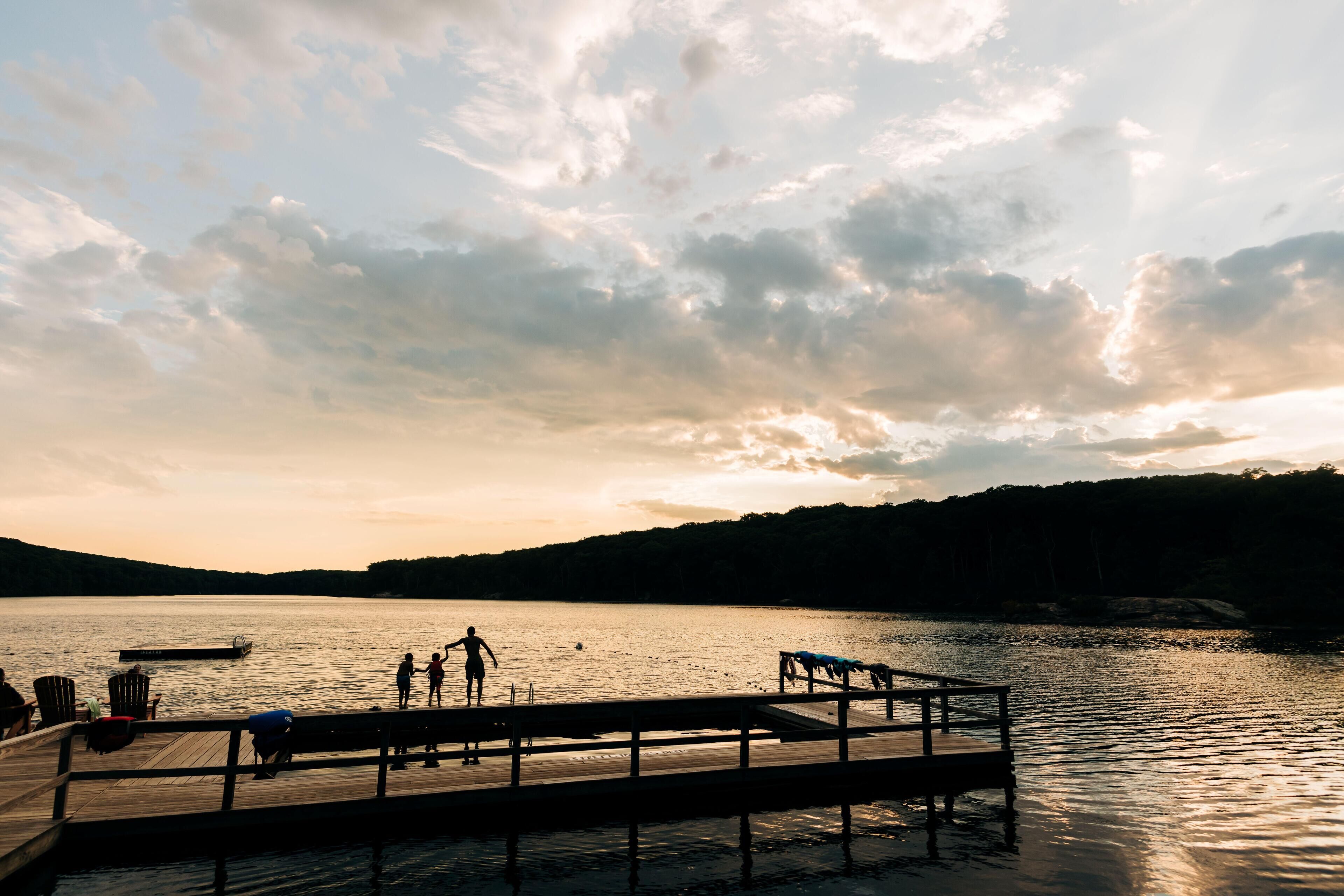 A wooden pier extending into a calm lake with a sunset in the background.