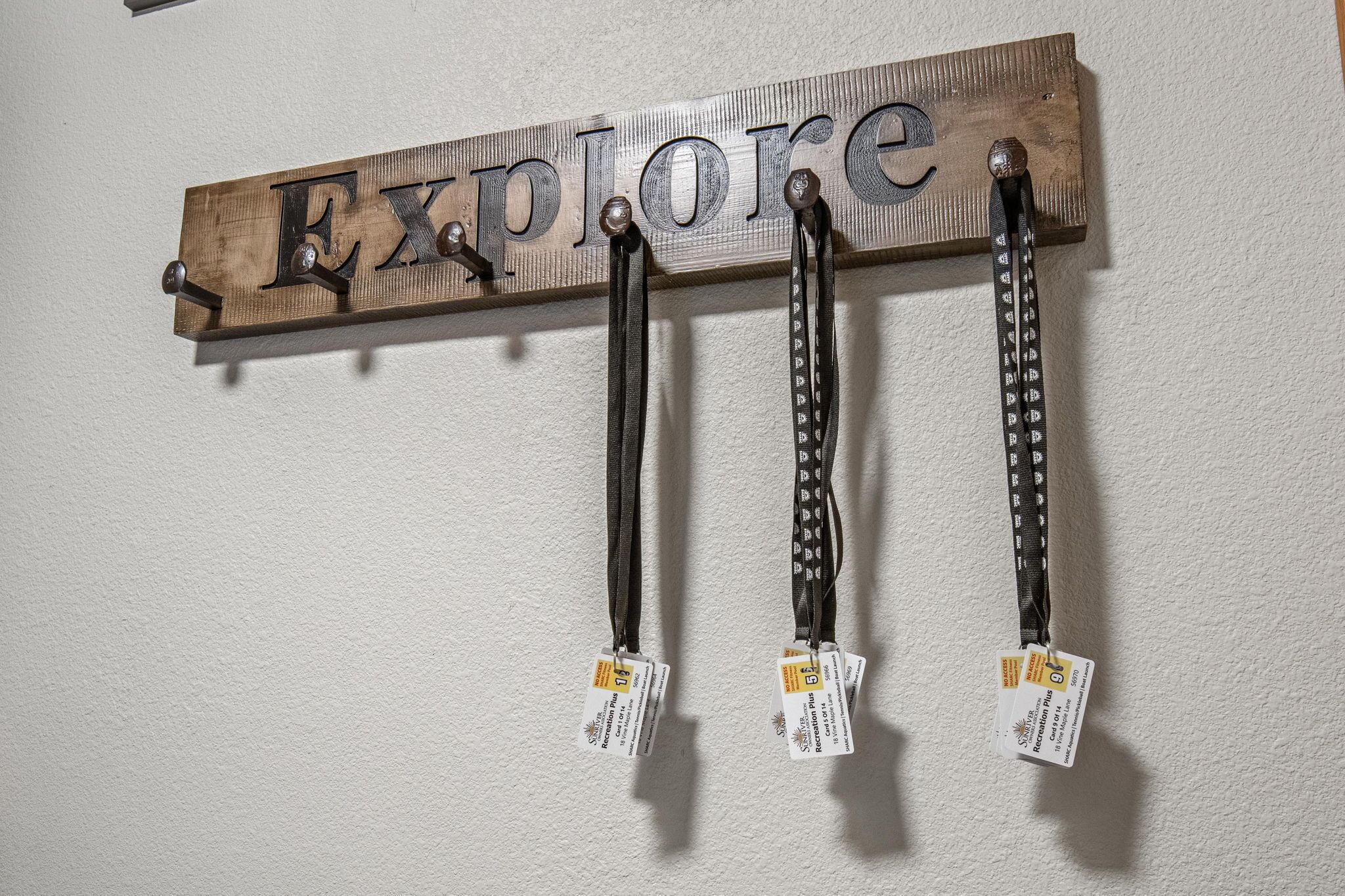 Une pancarte en bois sur laquelle est inscrit le mot « Explore », ainsi que trois porte-badges avec des étiquettes qui y sont attachés.