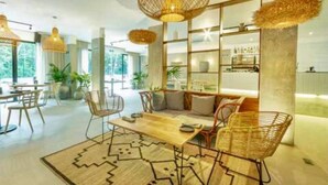 A modern interior with a dining area, wicker furniture, and a large bookshelf.