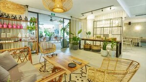 A modern hotel lobby with wicker furniture, a central table, and a display of bottles. - Tuk Tierra! Stylish one-bedroom apartment ny HeusHaven is designed for comfort and adventure. (Tulum)