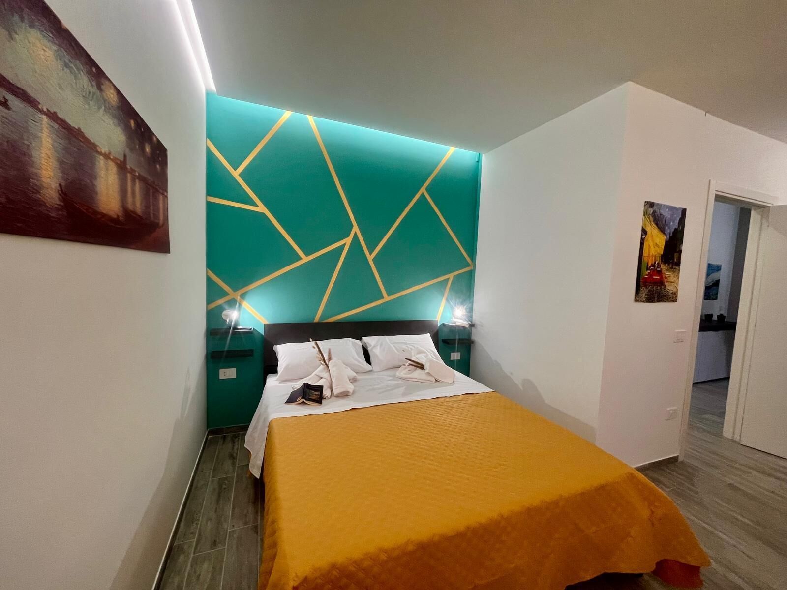 A modern hotel room with a geometric-patterned headboard, a neatly made bed, and a bright yellow throw blanket.