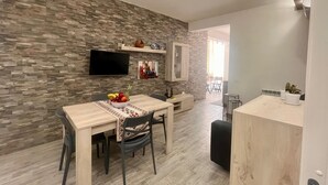Una cocina moderna con protector mural de piedra, una mesa de comedor de madera y un televisor empotrado.
