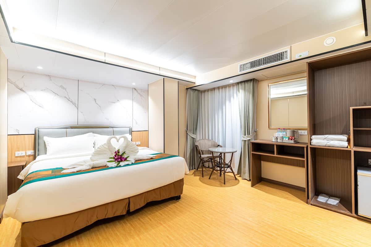 Une chambre d’hôtel avec un lit bien fait, un bureau, une chaise et une armoire.