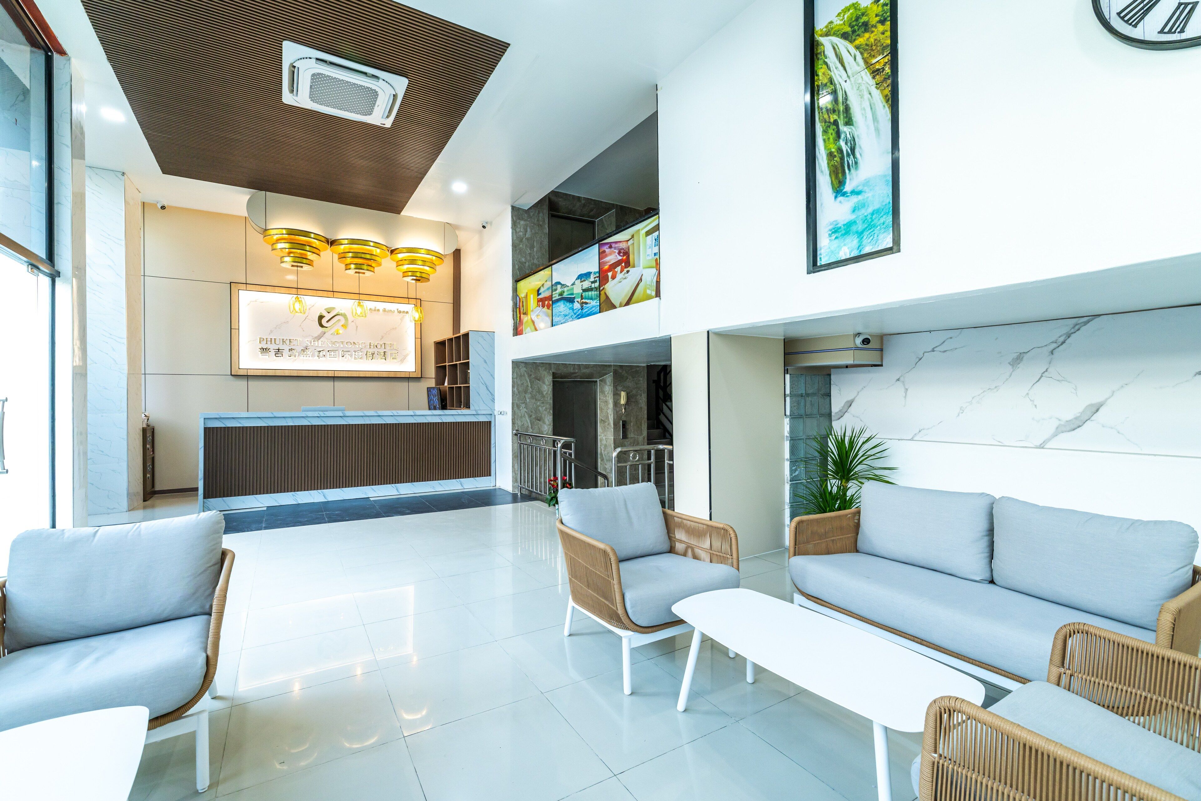 A modern hotel lobby with a reception desk, seating area, and artwork on the walls.