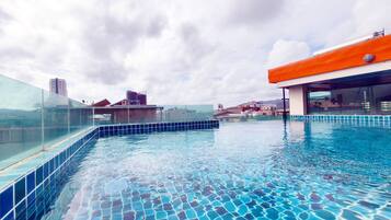 Alberca al aire libre, sombrillas en la alberca y camastros