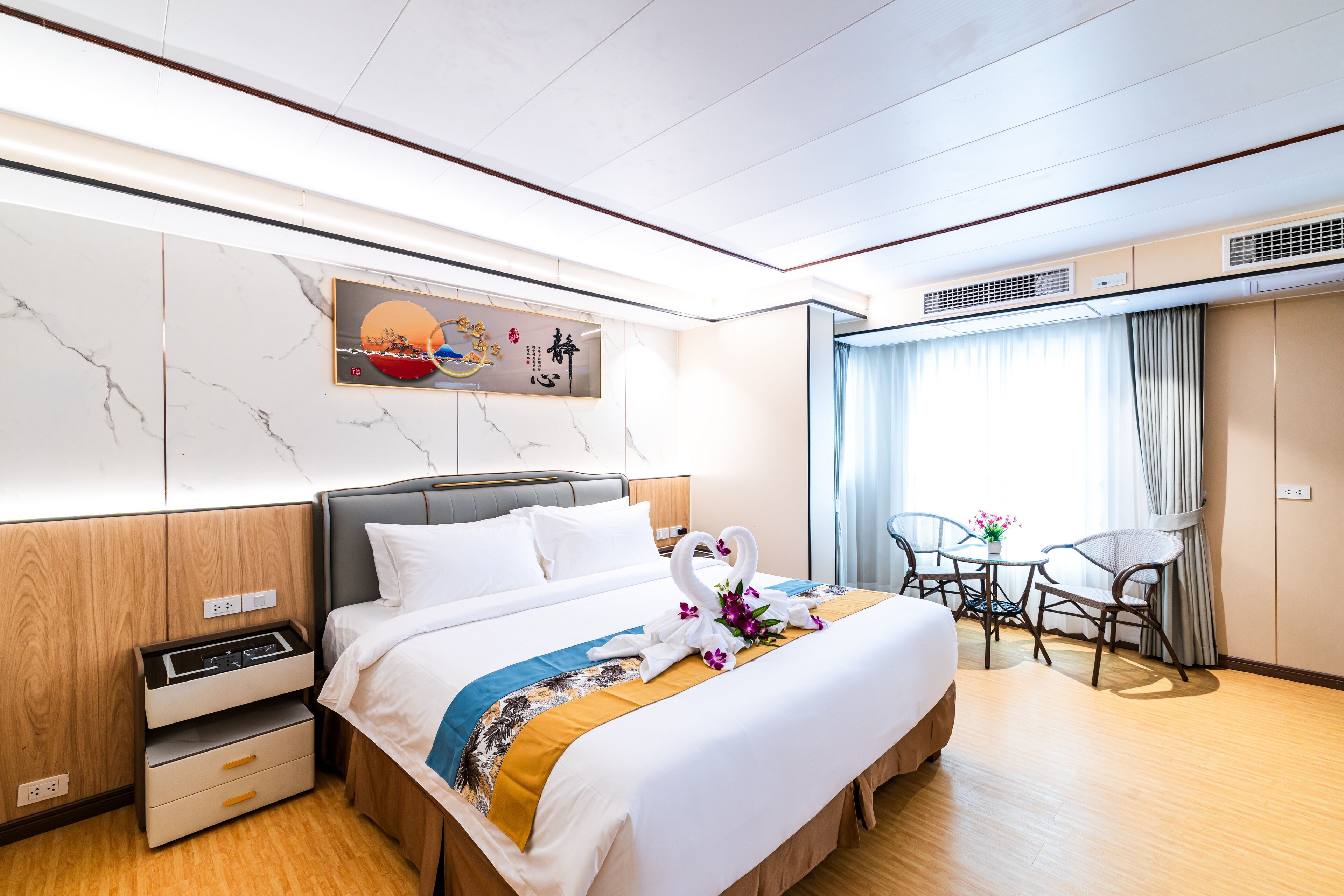 Una habitación de hotel con cama, mesita de noche y una pequeña mesa con sillas.