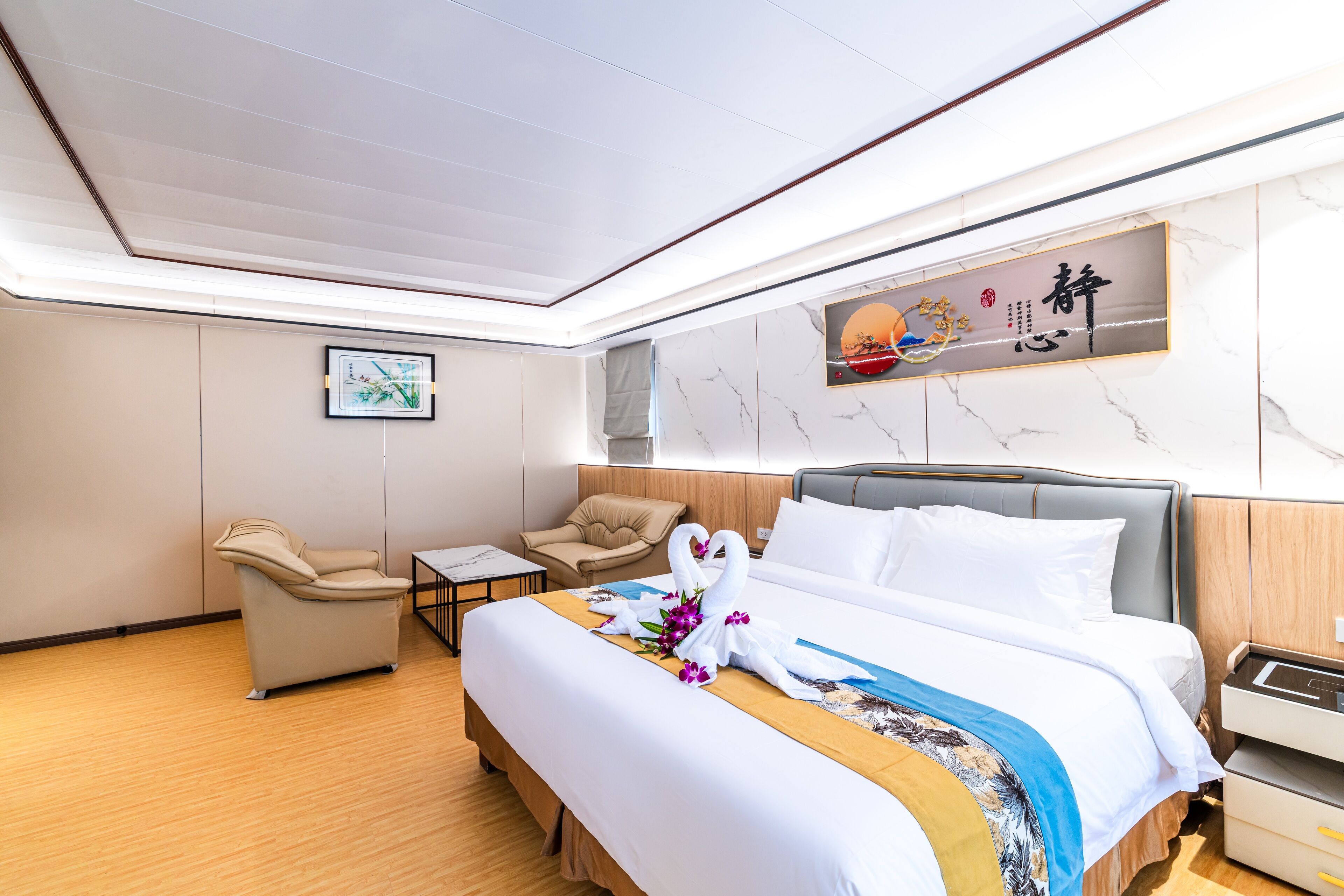 A hotel room with a large bed, a sofa, a desk, and a wall-mounted artwork.