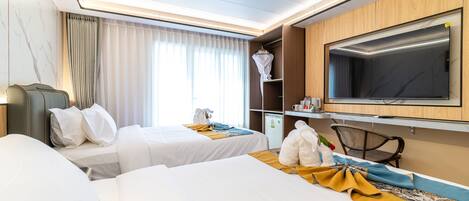 A hotel room with two beds, a TV, a minibar, and a large window with curtains.