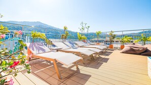 A rooftop lounge with sun loungers and potted plants. - Phuket Patong Buri Resort (Patong)