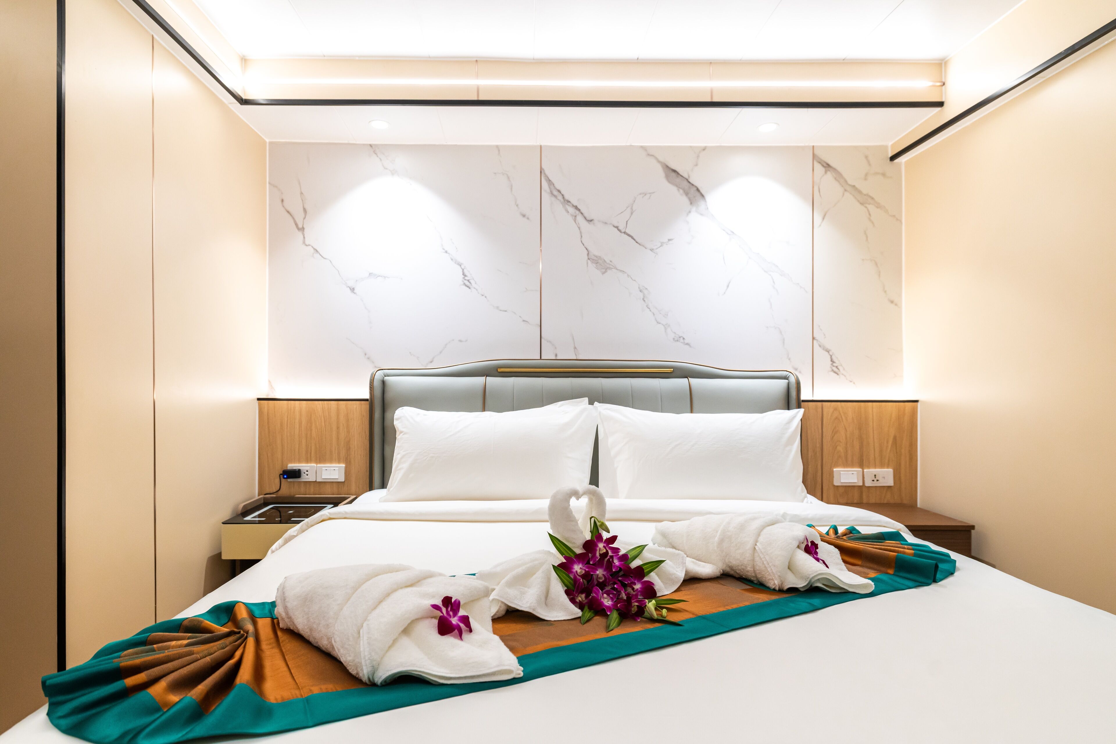A hotel room with a bed, a nightstand, and a wall with a marble pattern.