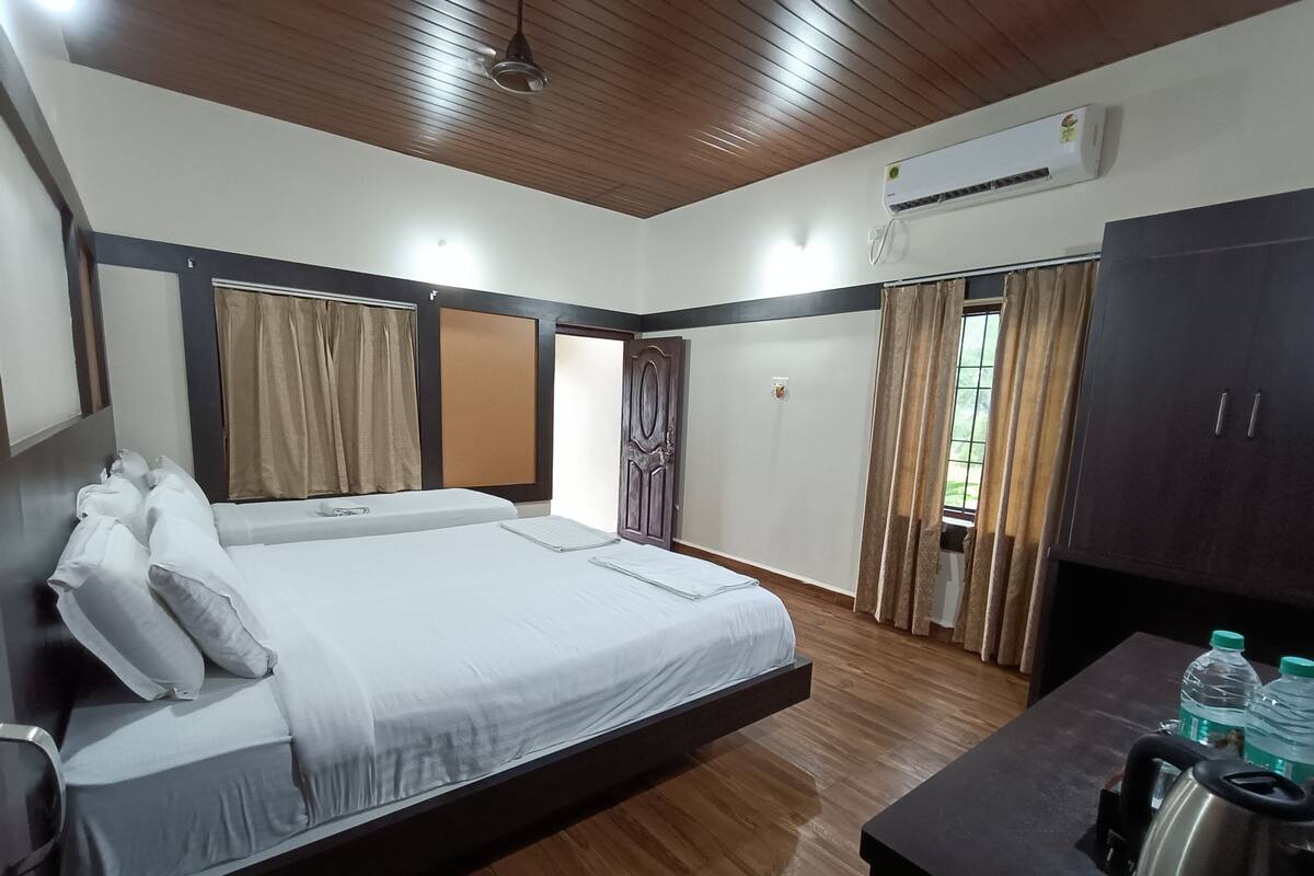 Une chambre dotée d’un grand lit, d’un plancher en bois, d’un climatiseur, d’un bureau avec une bouilloire et d’une armoire.