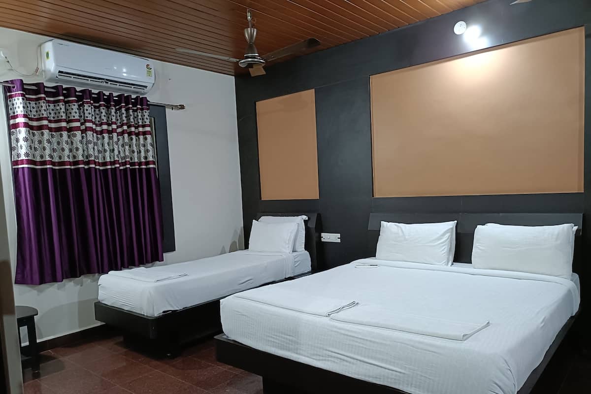 Une chambre d’hôtel avec deux lits simples, un grand lit, un appareil de climatisation, un ventilateur de plafond et une fenêtre avec des rideaux violets.