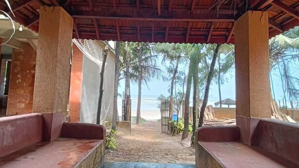 Un paseo techado que conduce a una playa con palmeras y vistas al océano.