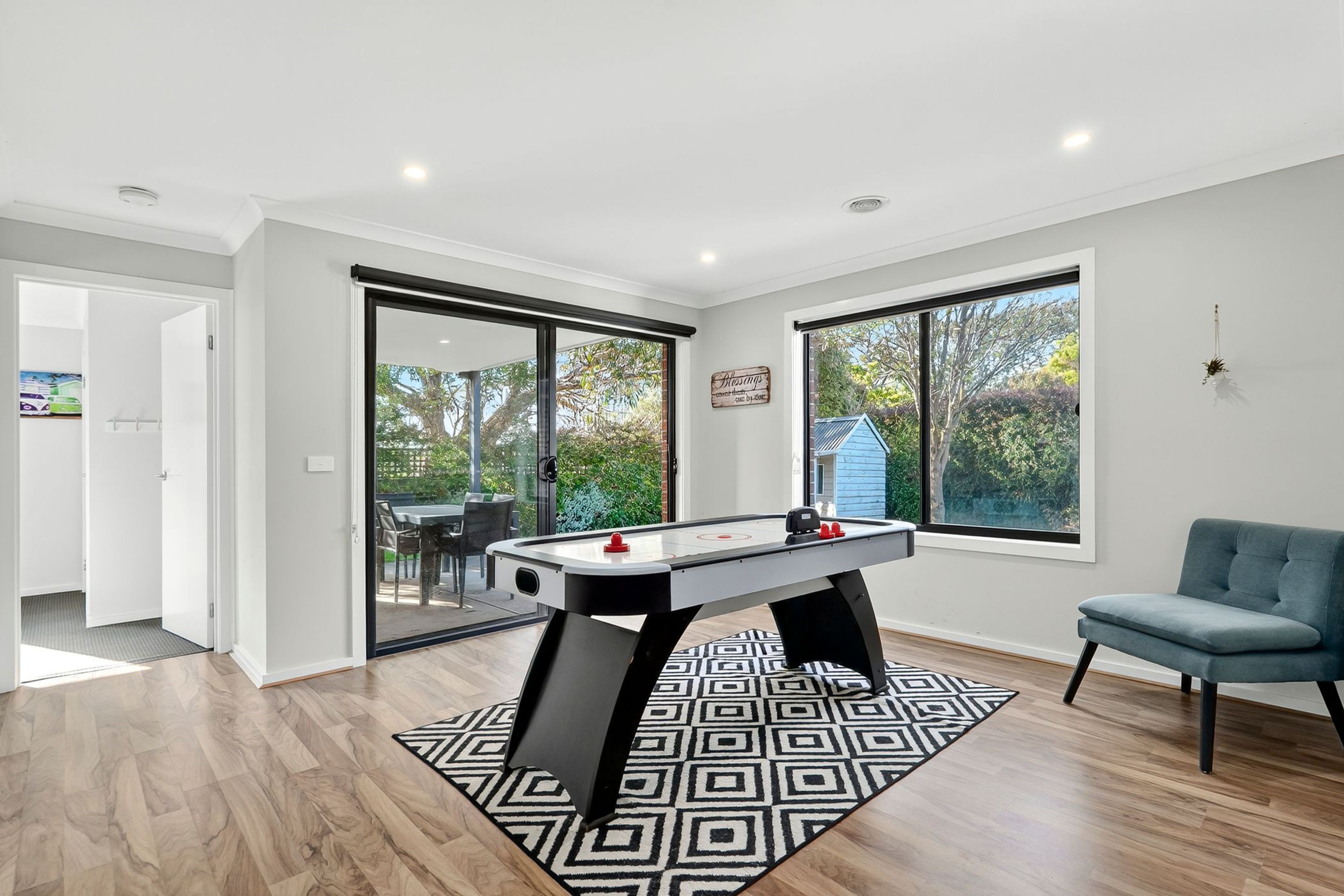 A modern living room with a foosball table, a blue sofa, and large windows offering a view of the outdoors.