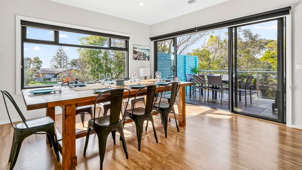 Un comedor con mesa y sillas de madera, ventanas amplias y vistas al exterior.