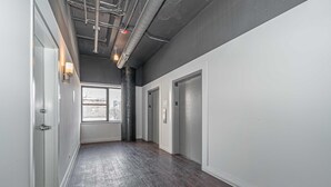 A hallway with a dark wooden floor, white walls, and a ceiling with exposed pipes and lighting fixtures. - Spacious 2BR in Chicago Near McCormick Sleeps 8 (Chicago)