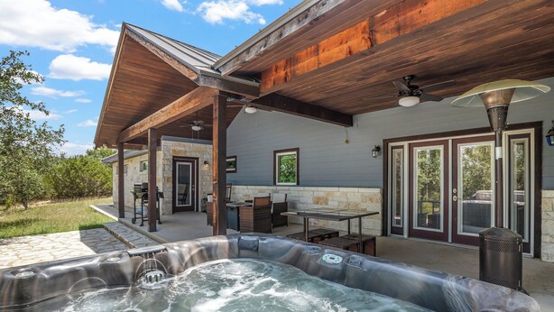 Un área de jacuzzi con pared de piedra, muelle de madera y asientos al aire libre.