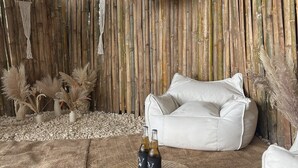A rustic room with a bamboo wall, a white cushioned seating area, and decorative plants. - DRAKO VILLAS (San Juan)