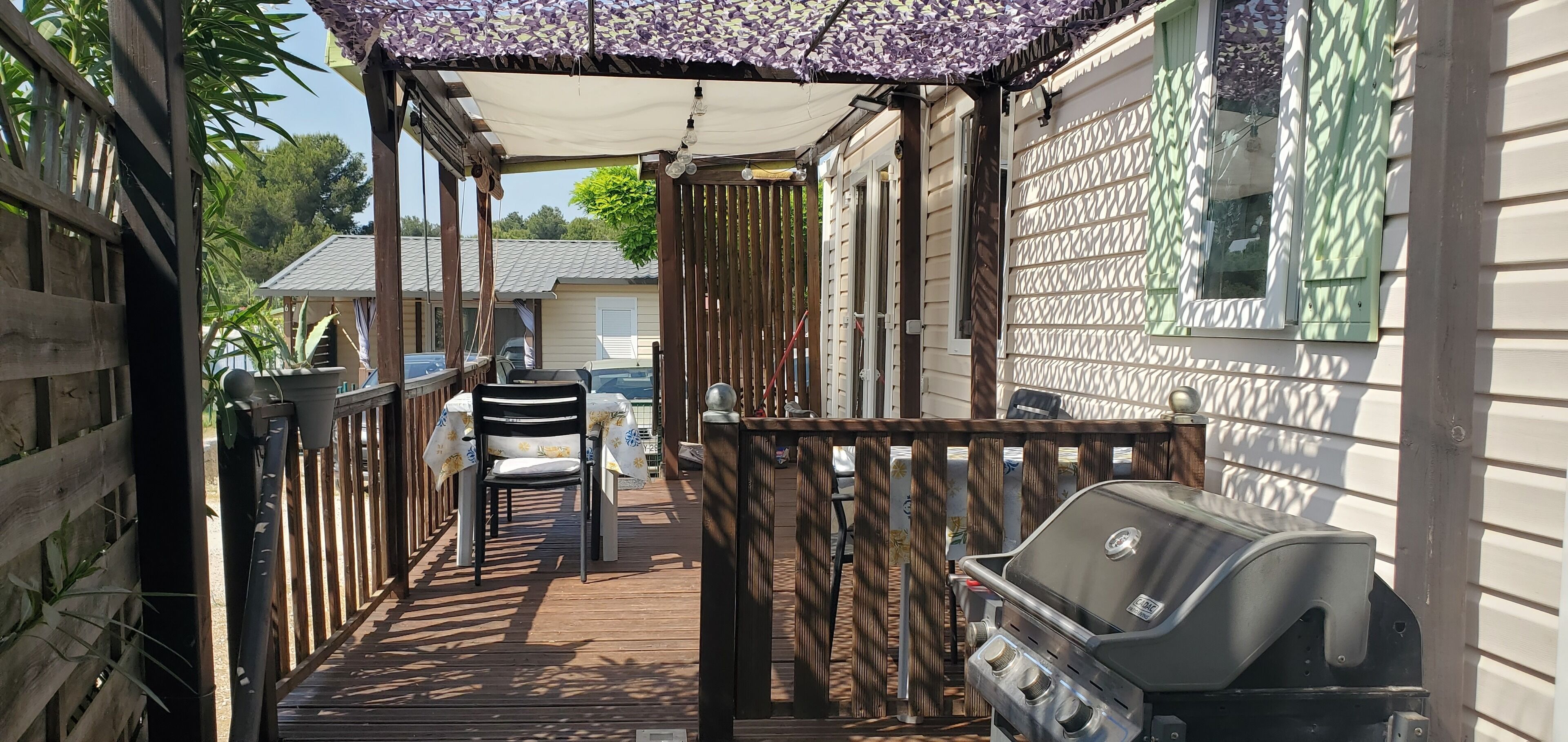 Um deck externo coberto com churrasqueira, cadeiras e uma mesa.