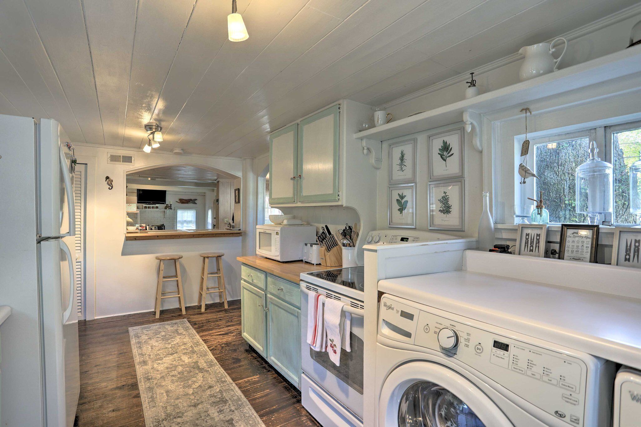 A kitchen with a washing machine, a microwave, and a sink.
