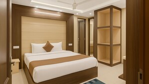 A hotel room with a large bed, wooden headboard, built-in wardrobe, and a ceiling fan. - Hotel Lajja Palace (Haridwar)