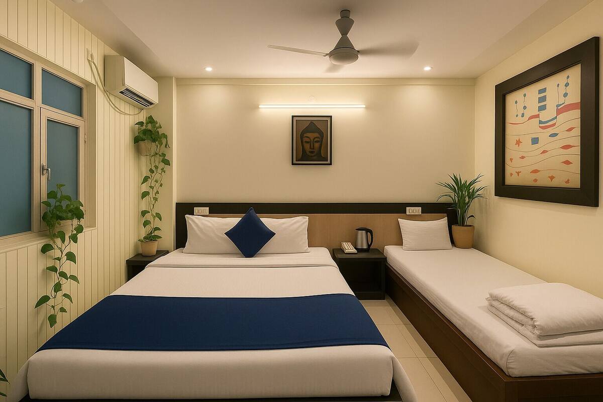 A hotel room with two beds, a ceiling fan, a framed Buddha statue, and a wall-mounted air conditioner.