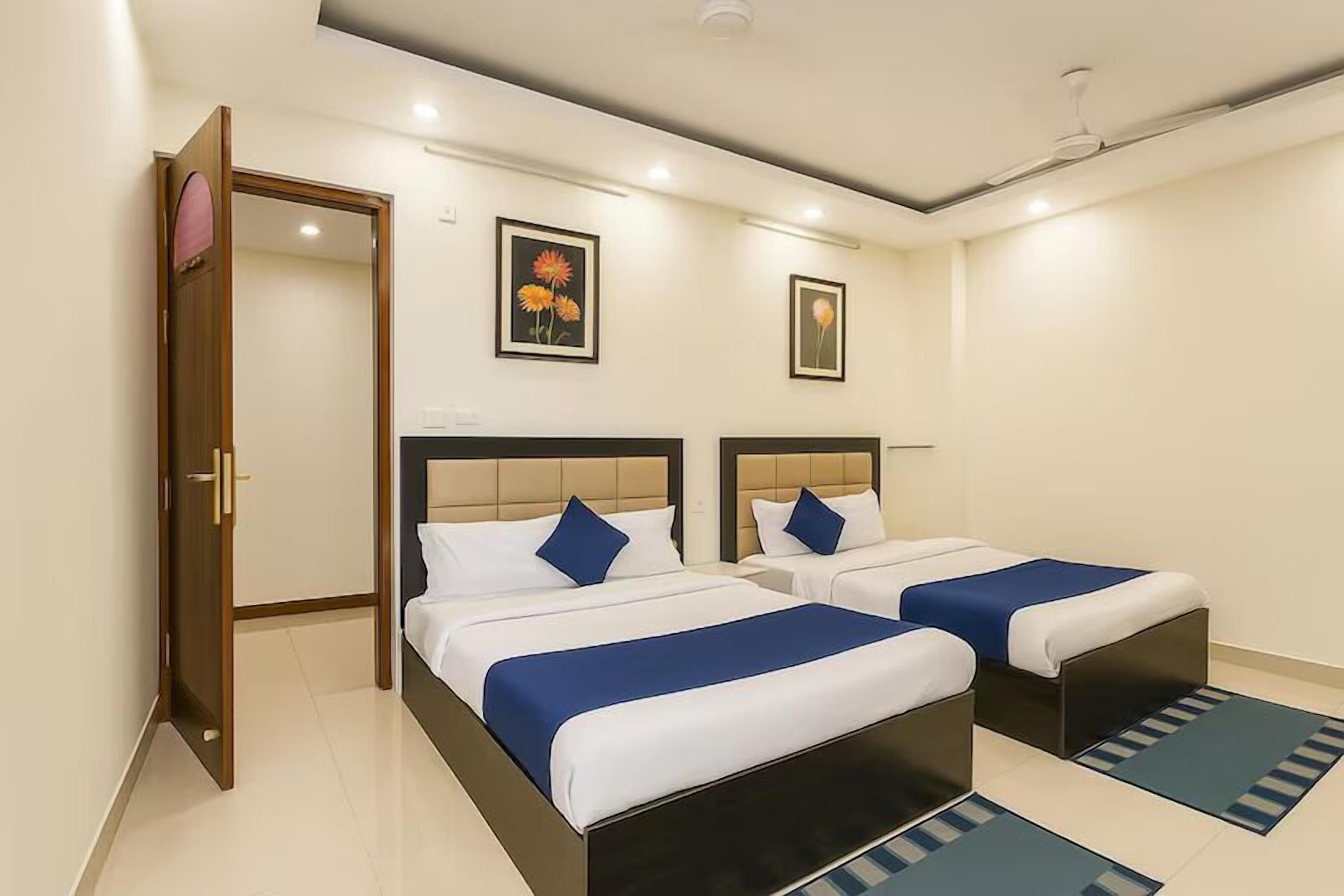 A hotel room with two beds, a wardrobe, and artwork on the walls.