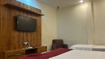 Habitación de hotel con un mueble bajo de madera para el televisor, un televisor de pantalla plana, un escritorio con una silla y dos camas individuales.