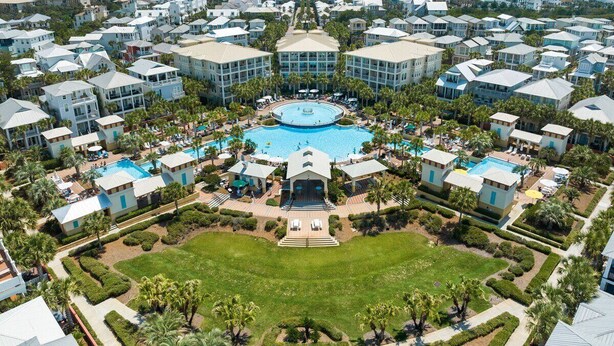 A resort with multiple buildings, a central pool, and a well-maintained lawn.