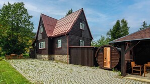 En rustik træhytte med et stejlt tag, en stenfondament og et træhegn.