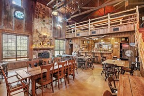 A rustic interior with wooden furniture, a stone fireplace, and a bar area. - Sister Creek Ranch - First Cabin - Hot Tub - Fireplace - Hill County Views (Boerne)