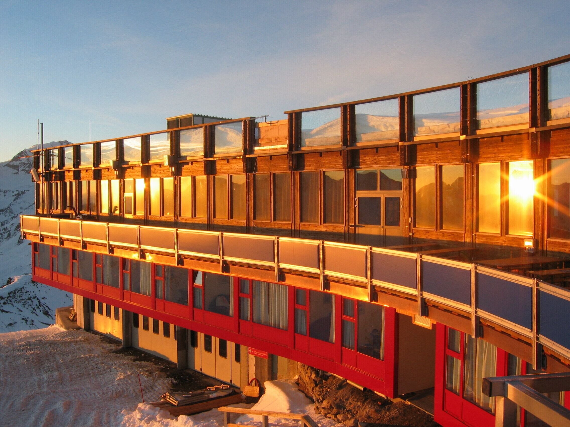 A multi-story building with large windows, a red lower section, and a wooden upper section.