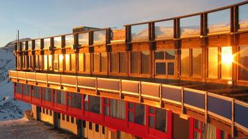 A multi-story building with large windows, a red lower section, and a wooden upper section.