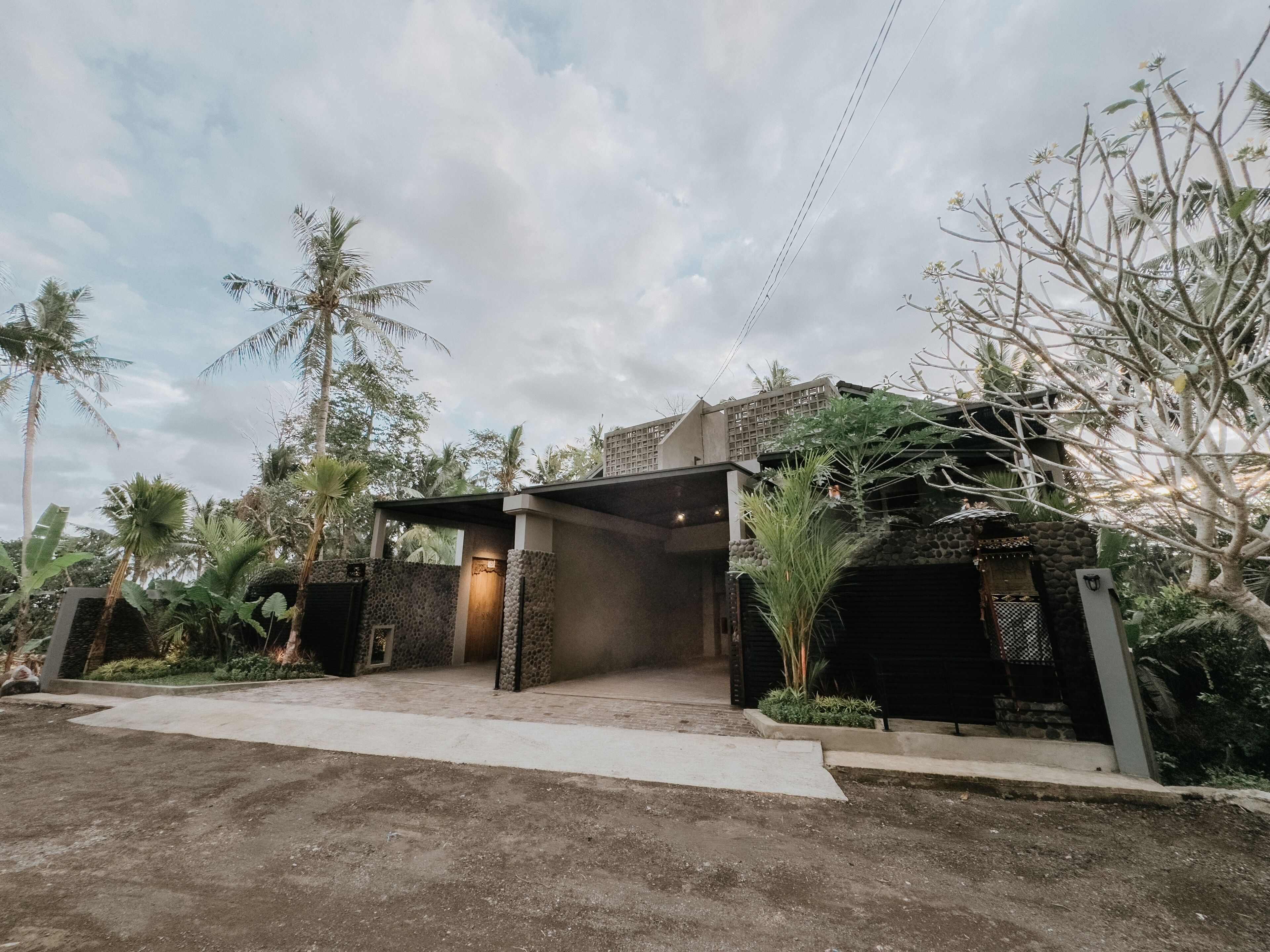 A modern house with a covered entrance, surrounded by tropical vegetation.