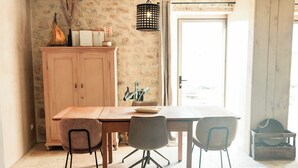 Een eethoek met een houten tafel, twee stoelen, een kast en een hanglamp.