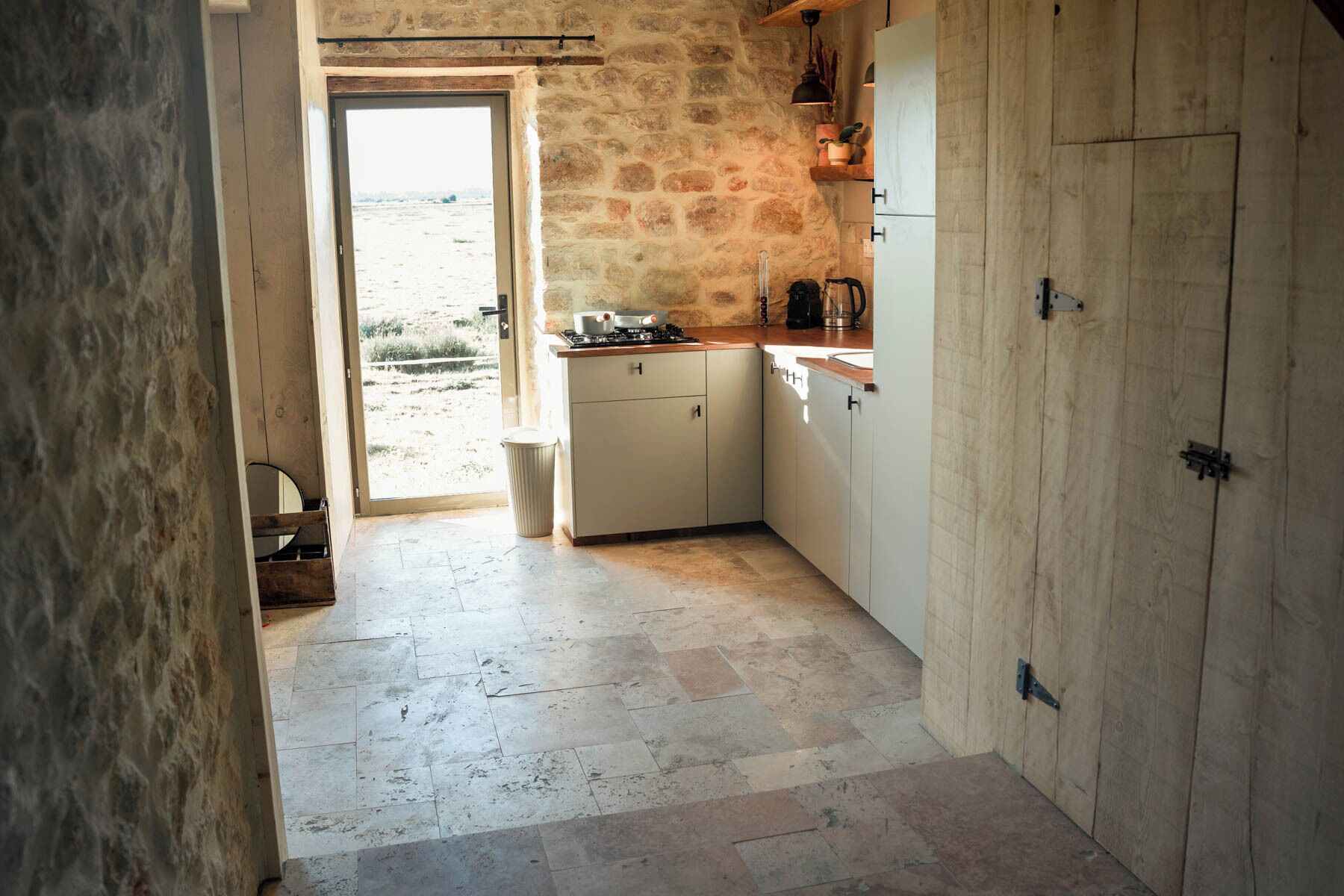 Une cuisine avec des murs en pierre, un évier et une cuisinière.