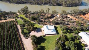 Vue aérienne d’une propriété comprenant un grand bâtiment, un vignoble et un lac.