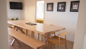 Un espace repas avec une longue table en bois, des bancs et des chaises.