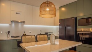 A modern kitchen with a central island, built-in appliances, and a hanging light fixture. - w Stunning 1BR in Miraflores (Lima)