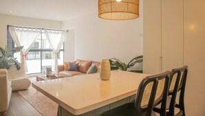 A modern living room with a large window, a sofa, a coffee table, and a dining area with chairs. - w Stunning 1BR in Miraflores (Lima)