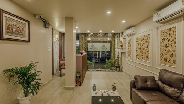 A hotel lobby with a reception desk, a brown leather sofa, potted plants, and a framed picture on the wall. - Bestaay- A Boutique Hotel (Near INFOCITY and KIIT) (Bhubaneshwar)