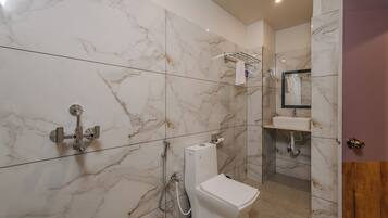 A bathroom with a toilet, sink, and shower area, all with marble walls and a modern design.