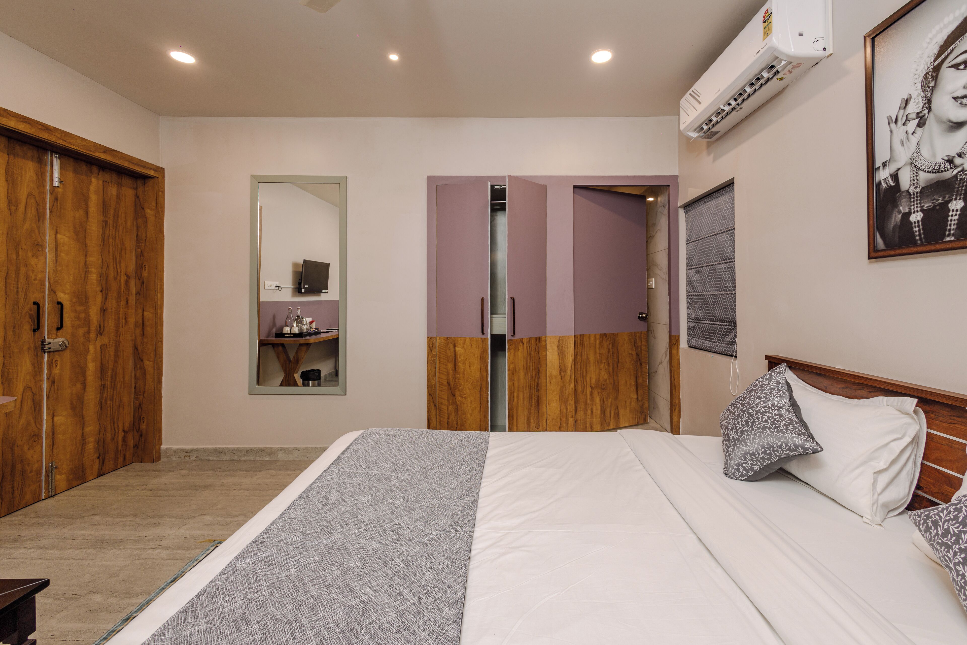 Une chambre avec un grand lit, une armoire, un miroir et un appareil de climatisation.