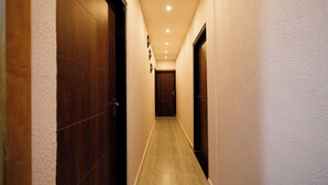 A narrow hallway with wooden doors on both sides, leading to a room at the end. - Bestaay- A Boutique Hotel (Near INFOCITY and KIIT) (Bhubaneshwar)
