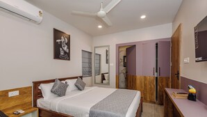 A bedroom with a wooden bed, a desk, a chair, a wardrobe, and a ceiling fan. - Bestaay- A Boutique Hotel (Near INFOCITY and KIIT) (Bhubaneshwar)